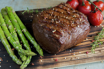 beef steak grilled with asparagus tomatoes spice on a wooden surface