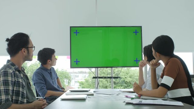Creative business team looking at green screen in the conference room applaud spokesperson.