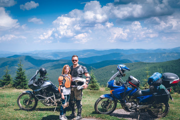 Happy young love couple in body armor and halmets stand on the top of the mountain, with big adventure motorcycle, travel togather, jorney, copy spase, mountains dirt road, enduro road trip