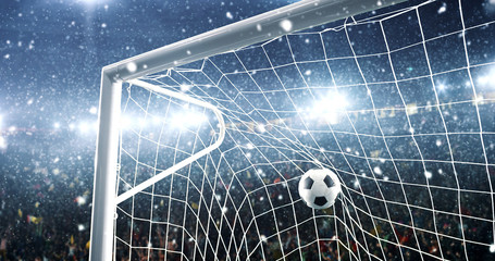 Photo of the ball that flies into a goal on a professional soccer stadium while it's snowing