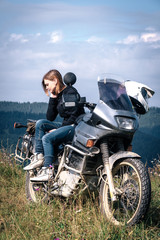 A girl stand alone on the top of the mountain a with big adventure touring motorcycle with bags and camping equipment, off road travel jorney, traveling together, couple, tent camp, vertical photo
