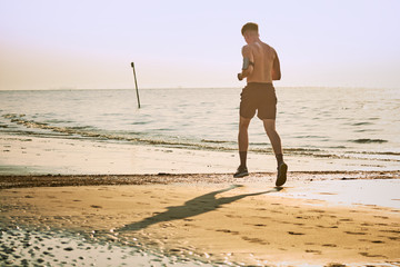 Uomo che corre sulla spiaggia all'alba