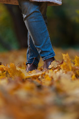 Close-up - female foots in autumn leaves ground. Happy fall time