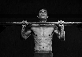 Muscular male athlete doing pull up exercise on horizontal bar. sports, fitness concept.