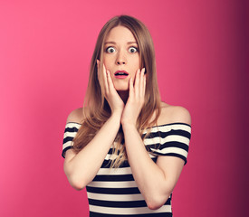 Shocked beautiful woman with opened mouth and big eyes looking. Closeup toned portrait on pink background with empty copy space