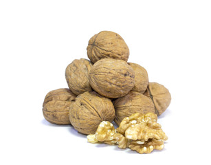 Walnut kernels in front of pyramid of walnut shells isolated on white background.