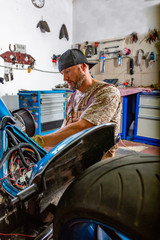 Side view portrait of man working in garage repairing motorcycle