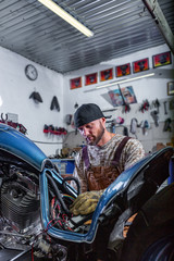 Naklejka premium Side view portrait of man working in garage repairing motorcycle