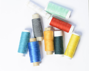 color threads for sewing on a white textured background