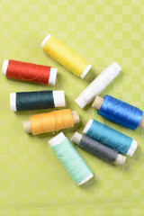 Colorful thread in spools on green background