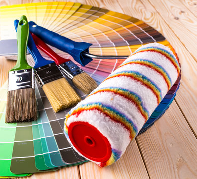 Painter and decorator work table with house project, color swatches, painting roller and paint brushes