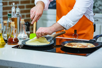 kitchen Preparation: the chef fries fresh pancakes in two pans