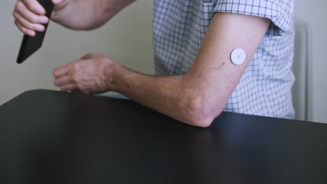 A man hands brings to the hand the smartphone for measuring glucose in the blood