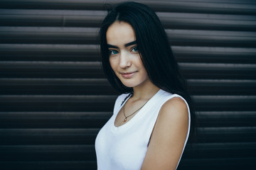 Female wearing white top standing over brown background