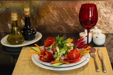 a plate of Turkish Coban salad,glass,fork,knife and wicker service napkins on the black background for restaurant and cafe concept.