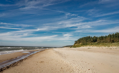 Coastal area in Lithuania Coastal scenery with sandy beach, dunes with marram grass and rough sea on a clear summer day with blue sky.