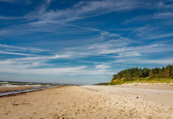 Coastal area in Lithuania Coastal scenery with sandy beach, dunes with marram grass and rough sea on a clear summer day with blue sky.