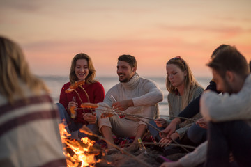 Group Of Young Friends Sitting By The Fire at beach
