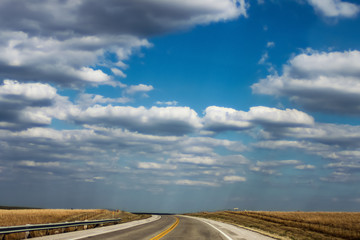 Driving on the rolling hills of Northeastern Oklahoma under a big blue sky with fluffy clouds and...