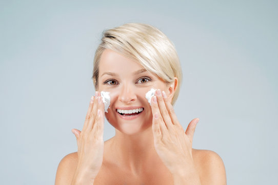 Happy woman with foam for washing on her face. Perfect clean skin.