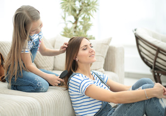 little girl combs her mother's hair
