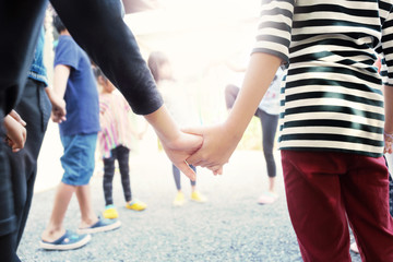 Obraz premium Two young child's hands holding each other,soft focus and color toned.