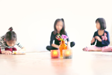 Fototapeta premium Beautiful flower in a glass bottle with blurry of Asian girls working art as background. Soft and selective focus for art concept.