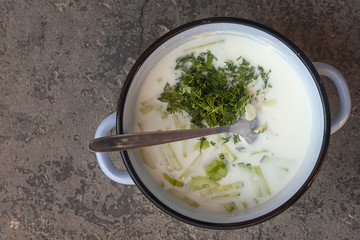 Summer cold soup. Okroshka. Preparing cold soup with fresh herbs.