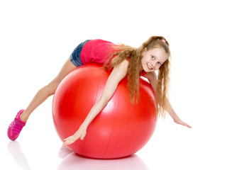 little girl doing exercises on a big ball for fitness.