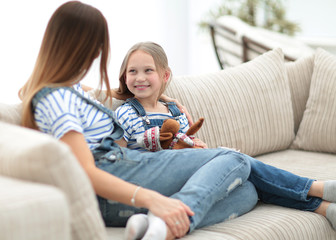 mom and little daughter sitting on the couch in a cozy living room