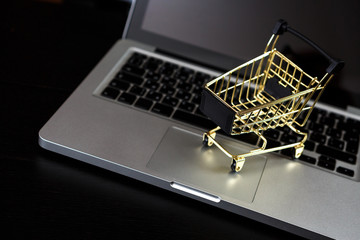 Online shopping bank card nearby a laptop and mini shopping cart