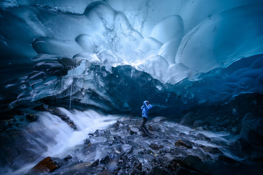 A hiker photographs the opening of a moulin (a tunnel though the glacier) in the ceiling of a glacial cave under the Mendenhall Glacier. 