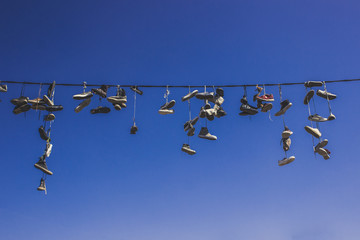 festival teenagers traditional funny vintage colorful hippie informal concept of hanging shoes on cord  on blue sky background with empty space for copy or text