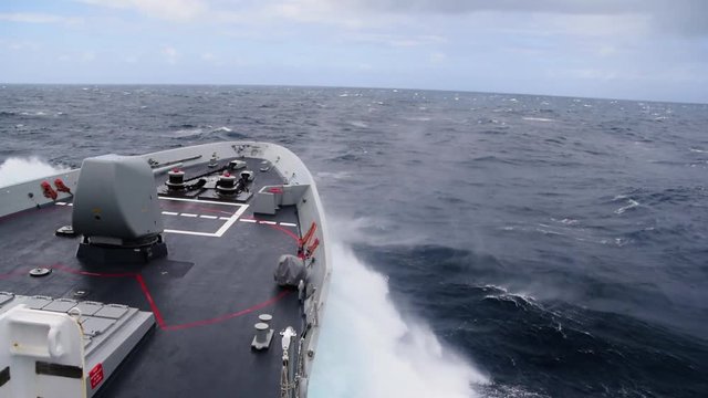 A Navy Destroyer underway through the Atlantic Ocean. View of the bow cutting the waves from the bridge.