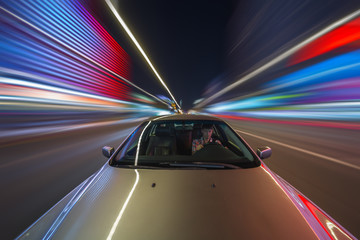 Obraz premium Blurred downtown look from fast driving car to back side and driver at summer twilight. Longexposure shot.