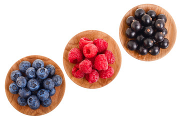blueberry raspberry black currant in wooden bowl isolated on white background. Top view. Set or collection