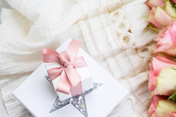 Pink roses bouquet with pile of gift boxes on wedding dress backgroud, top view