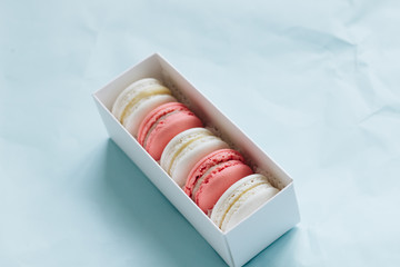 Composition of delicious macaroons on blue table, sweet dessert