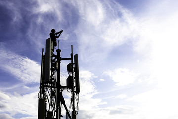 silhouette technician installing communication tool on high pole