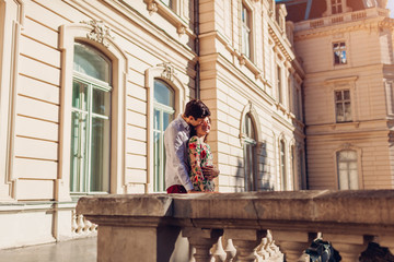 Young happy couple in love hugging outdoors. Romantic man and woman walking by old city architecture