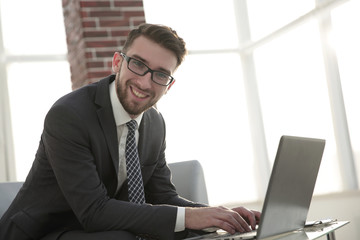 businessman with glasses is sitting at the desk in the office