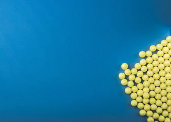 a lot of yellow round vitamins on a blue background.