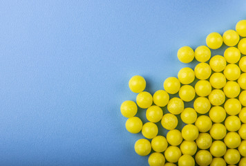 a lot of yellow round vitamins on a blue background.