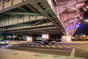 Cars move at night under the bridge in the city