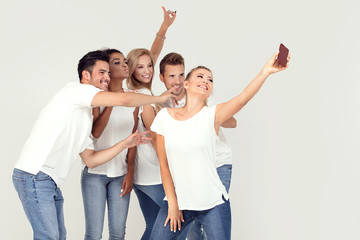 Group of young smiling people taking selfie.