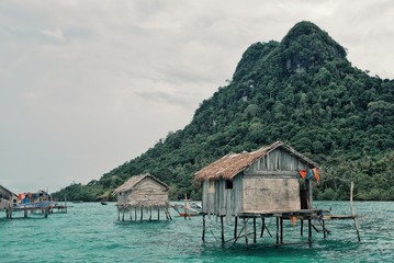 stilt houses in a bajau sea gypsy village next to a small island rock outcrop