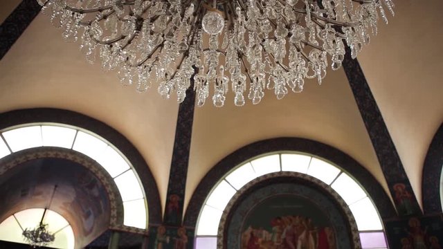 A big crystal chandelier hanging from the ceiling of a Greek Orthodox church.