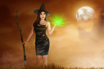 Pretty asian witch woman with broomstick and magic fire on her hand