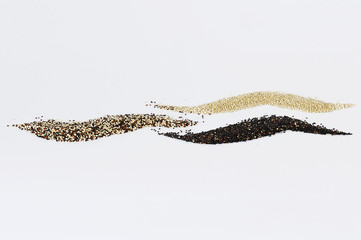 Grains of black, tricolor and white quinoa isolated on white background.