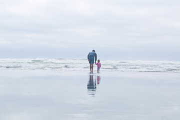 man and toddler girl walking on the beach